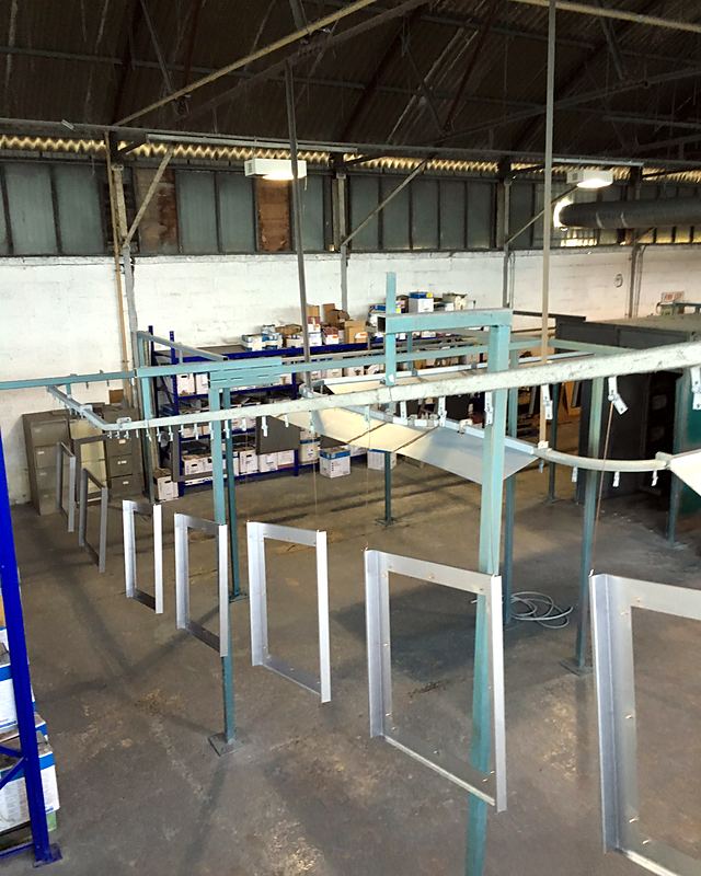 Aluminium frames hung in a row on the overhead line in a Vale workshop